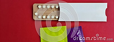 Condoms and birth control pills on red background, flat lay Stock Photo