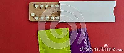 Condoms and birth control pills on red background. Safe sex Stock Photo