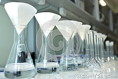 Conducting a chemical experiment in a laboratory. Colored flasks with chemical reagents. Many glass medical flasks in Stock Photo