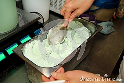 Confectioner in chef uniform is working at ice cream factory. Woman is decorations of italian creamy mint ice cream flavors. Stock Photo