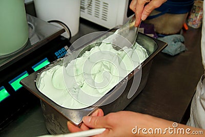 Confectioner in chef uniform is working at ice cream factory. Woman is decorations of italian creamy mint ice cream flavors. Stock Photo