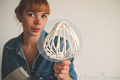 Confectioner girl holding an electric whisk is preparing a cake. Concept ingredients for cooking flour products or dessert Stock Photo