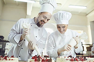 Confectioners with a bag for the cream will decorate the cake. Stock Photo