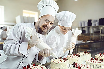 Confectioners with a bag for the cream will decorate the cake. Stock Photo