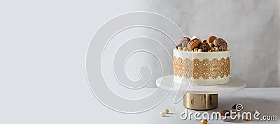 Confectionery, bakery banner. Festive cake decorated with chocolate candies and macaroons on the stand on gray background. Copy Stock Photo