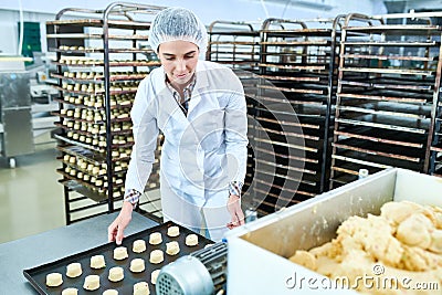 Confectionery factory worker holding tray with uncooked pastry Stock Photo