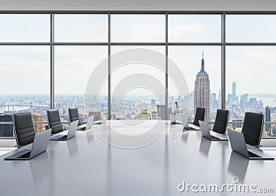 A conference room equipped by modern laptops in a modern panoramic office in New York. Black leather chairs and a white table. Stock Photo