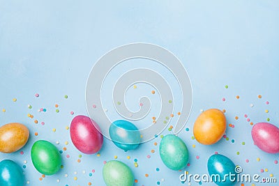 Confetti and colorful eggs on blue table top view. Easter greeting banner. Copy space for text. Stock Photo