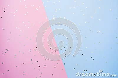 Confetti of gold stars glisten on a pink blue background. Festive holiday pastel backdrop Stock Photo