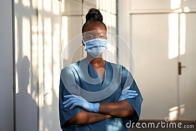 Confident african nurse wear blue uniform, face mask, standing in hospital. Stock Photo