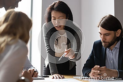 Confident Asian businesswoman talk with diverse colleagues at meeting Stock Photo