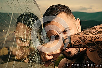 Confident attractive man with serious face cracked glass. Dangerous criminal, hooligan guy on cracked bullet glass. Stock Photo