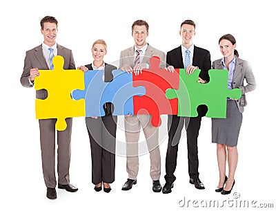 Confident business people holding colorful jigsaw puzzle Stock Photo