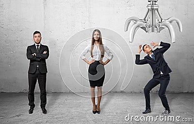 Confident business people standing straight and scared businessman shielding himself from the giant mechanical claw Stock Photo