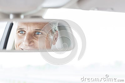 Confident businessman reflecting in rear-view mirror of car Stock Photo