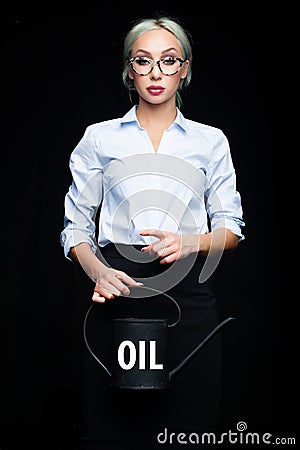 Confident businesswoman holding black watering can with word petrol. Success, wealth, business, energy concept. Stock Photo