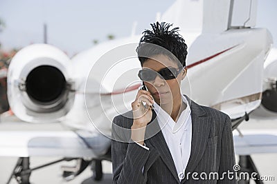 Confident Businesswoman Using Cellphone At Airfield Stock Photo