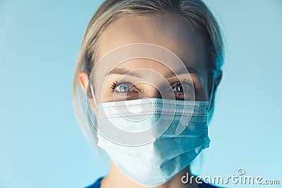 Confident caucasian nurse lady wearing professional mask, educates about safety. close up studio shot, blue background. Stock Photo
