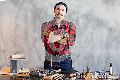 Confident craftsman with crossed arms standing at workplace Stock Photo