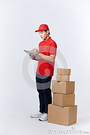 Confident deliveryman. Cheerful young deliveryman holding a cardboard box while standing in front of the box stack Stock Photo