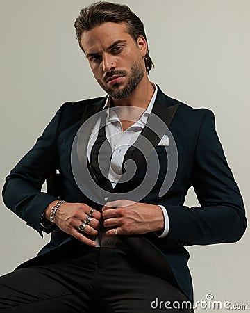 confident elegant man with open collar shirt unbuttoning tuxedo Stock Photo