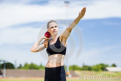 Confident female athlete preparing to throw shot put ball Stock Photo