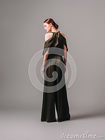 Confident ginger woman in dark silk jumpsuit. Womenâ€™s clothing, fashionable gown, halter dress. Stock Photo