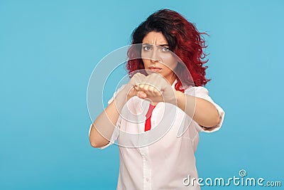 Confident hipster woman with fancy red hair in white shirt clenching fists to camera, courageously fighting threat Stock Photo