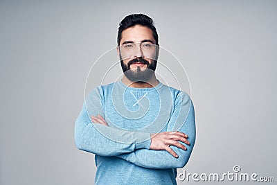 Confident Hispanic man in blue pullover standing with folded hands Stock Photo