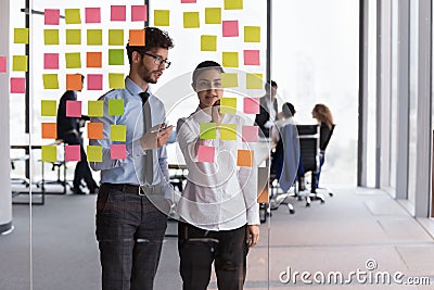 Confident Indian mentor woman teaching young Intern guy Stock Photo
