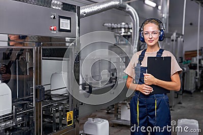 Confident industrial woman engineer in spectacles standing in factory at work place Stock Photo