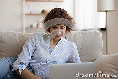 Confident lady recline on couch engaged in chatting by laptop Stock Photo