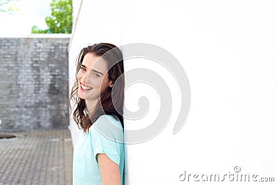 Confident lady smiling leaning against white wall Stock Photo