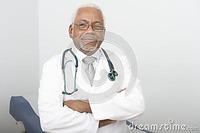 Confident Male Doctor Standing With Hands Folded Stock Photo