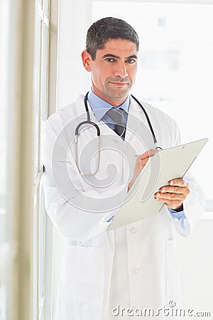 Confident male doctor writing on clipboard Stock Photo