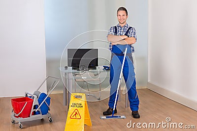 Confident male janitor with cleaning equipments Stock Photo