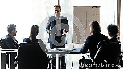 Confident male leader coach instructing interested diverse teammates. Stock Photo