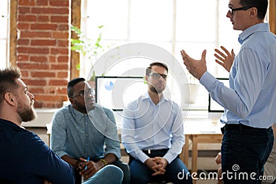 Confident male leader mentor coach speaking at diverse team meeting Stock Photo