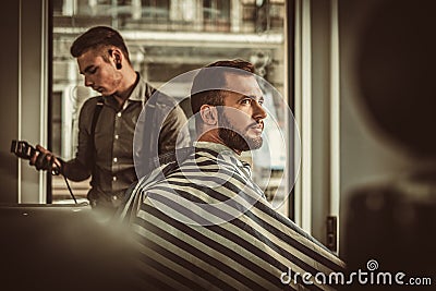 Confident man visiting hairstylist in barber shop. Stock Photo