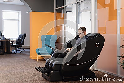 Man writing code while sitting in armchair in the office Stock Photo