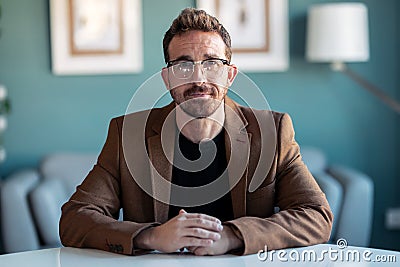 Confident mature man explaing something looking at camera while doing video call in the office at home Stock Photo