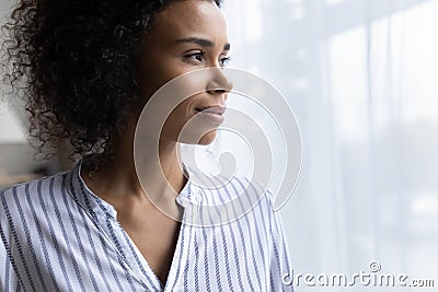 Confident millennial black woman stand by window look forward visualize Stock Photo