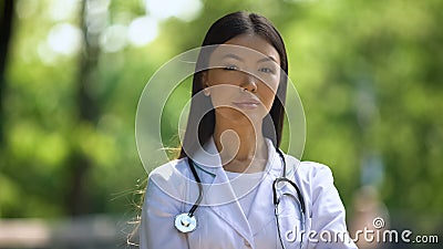 Confident nurse looking into camera in hospital park, medical profession, health Stock Photo