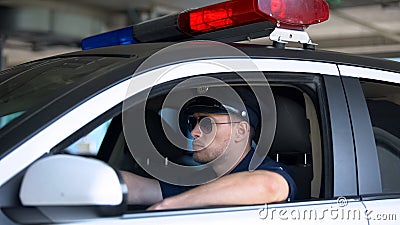 Confident policeman in sunglasses sitting in car, ready for area patrolling duty Stock Photo