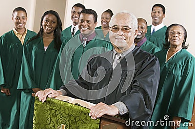 Confident Preacher Standing At Pulpit With Choir In Background Stock Photo