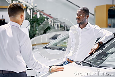 Confident salesman talk about characteristics of car to customer man Stock Photo