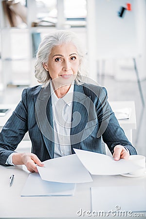 Confident senior businesswoman doing paperwork at workplace Stock Photo