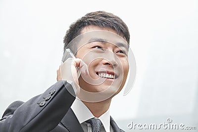 Confident, smiling businessman on his mobile phone outdoors in Beijing, China Stock Photo