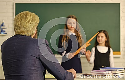 Confident students studying. Teacher and pupils working at desk together at the elementary school. disclose and develop Stock Photo
