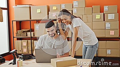 Confident team of two workers, a man and woman, laughing together while working on a laptop in the vibrant office, packaging Stock Photo